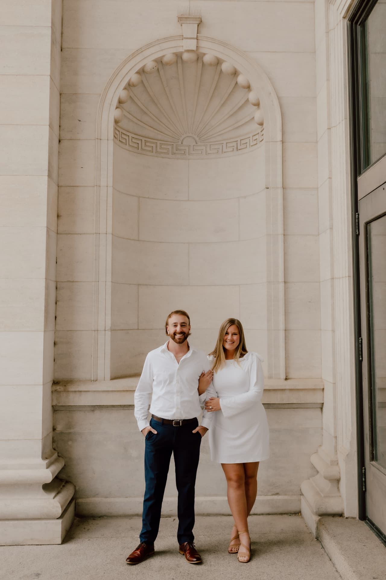 Couple standing together in front of a large stone archway